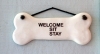 Photo of a dog bone shaped sign near front door that says, "Welcome, Sit, Stay"